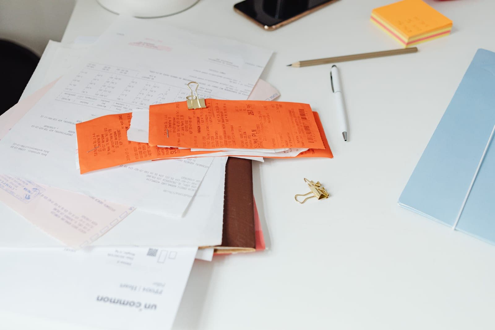 Desk covered with paper invoices, receipts and documents waiting to be processed and digitised