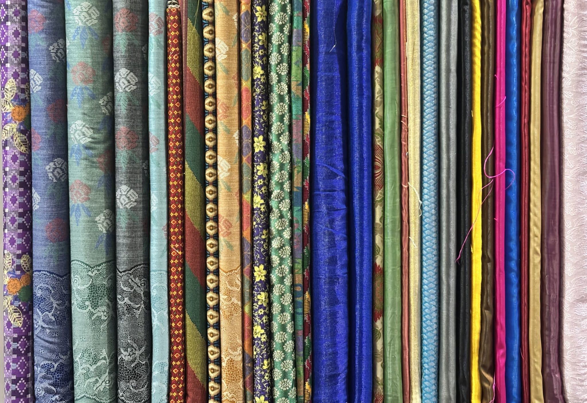 Rolls of fabric stacked in a textile warehouse representing dead stock