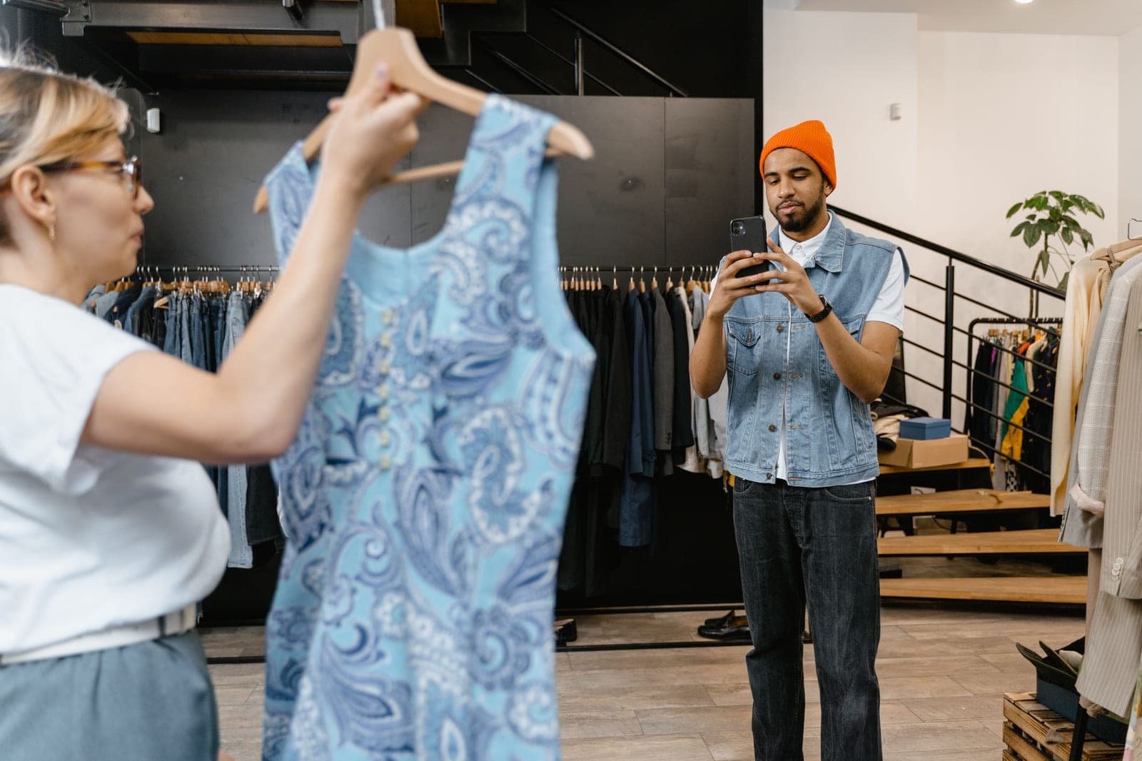 Person photographing a patterned garment on a hanger with a smartphone in a clothing store