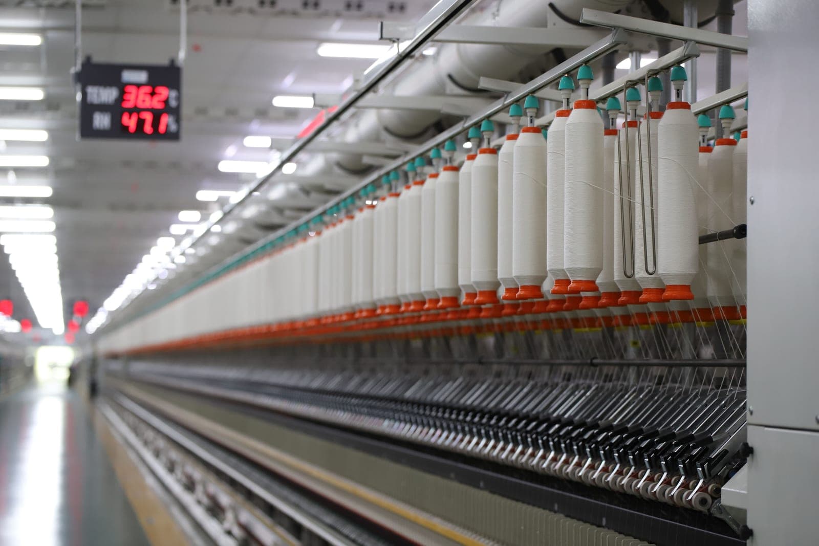 Modern computerised spinning machine with a digital display on a textile mill floor, representing AI in the textile industry