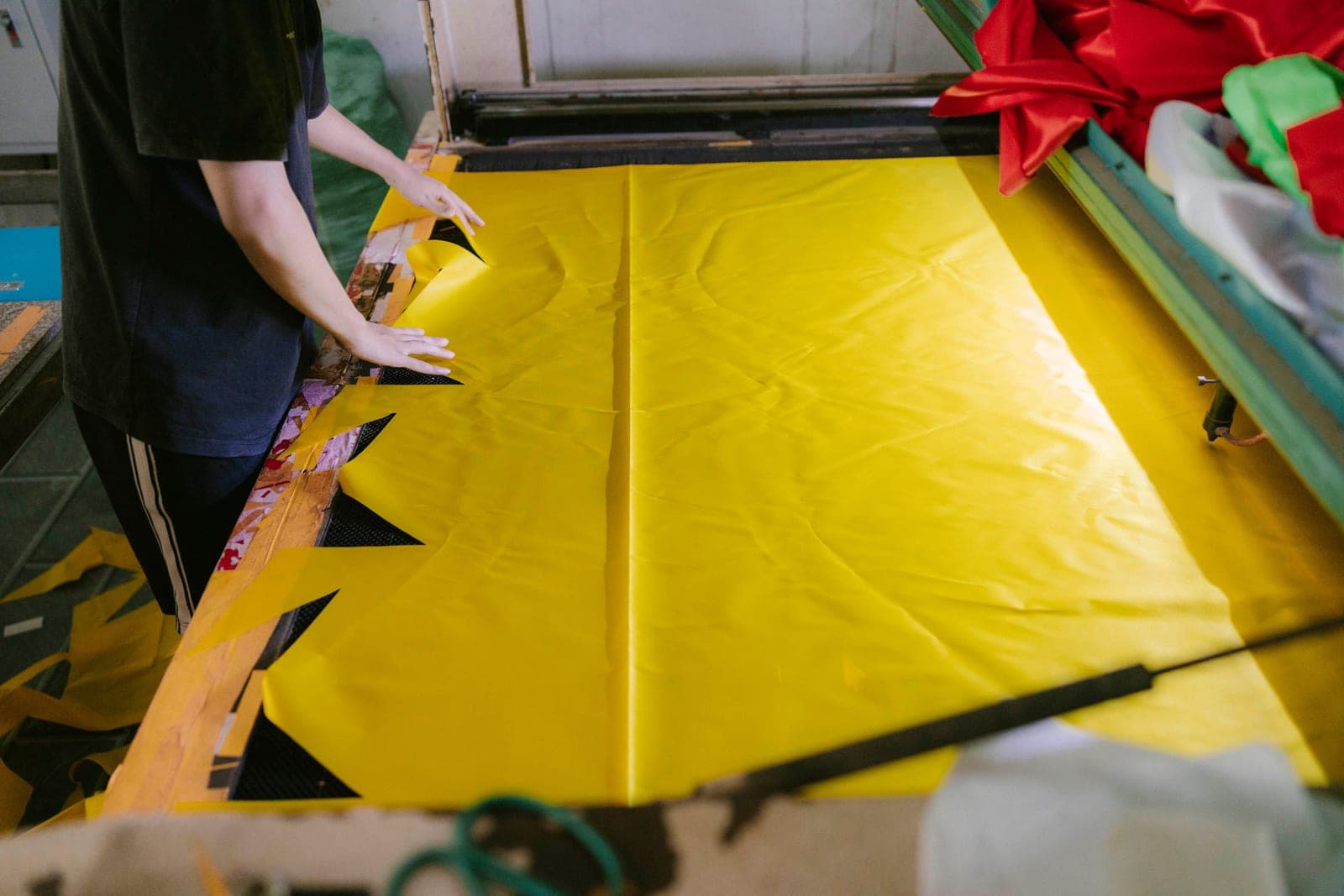 Worker spreading fabric on a cutting table with notches cut into the edge in a cutting room