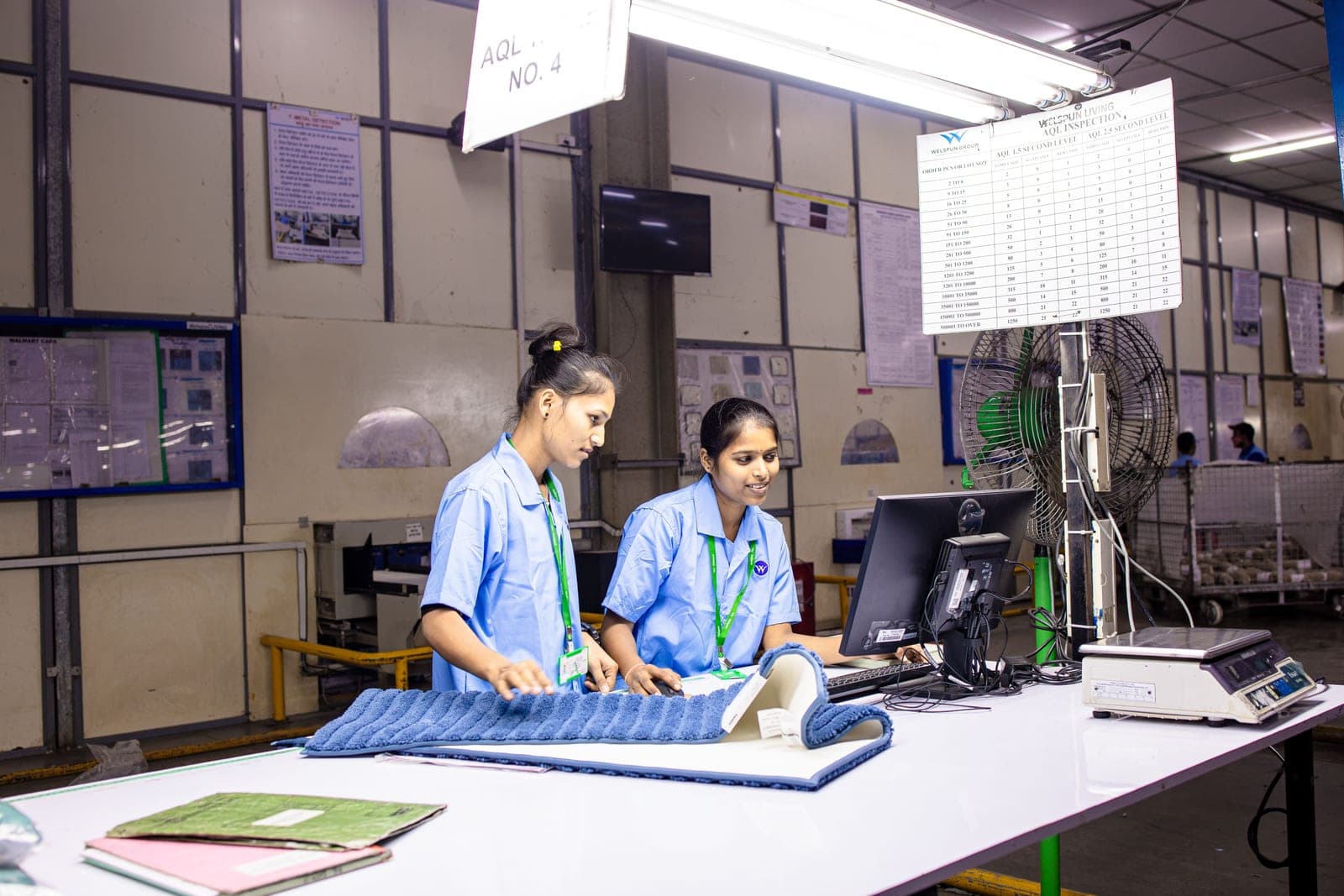 Textile quality-control workers inspecting fabric at an inspection station in a factory