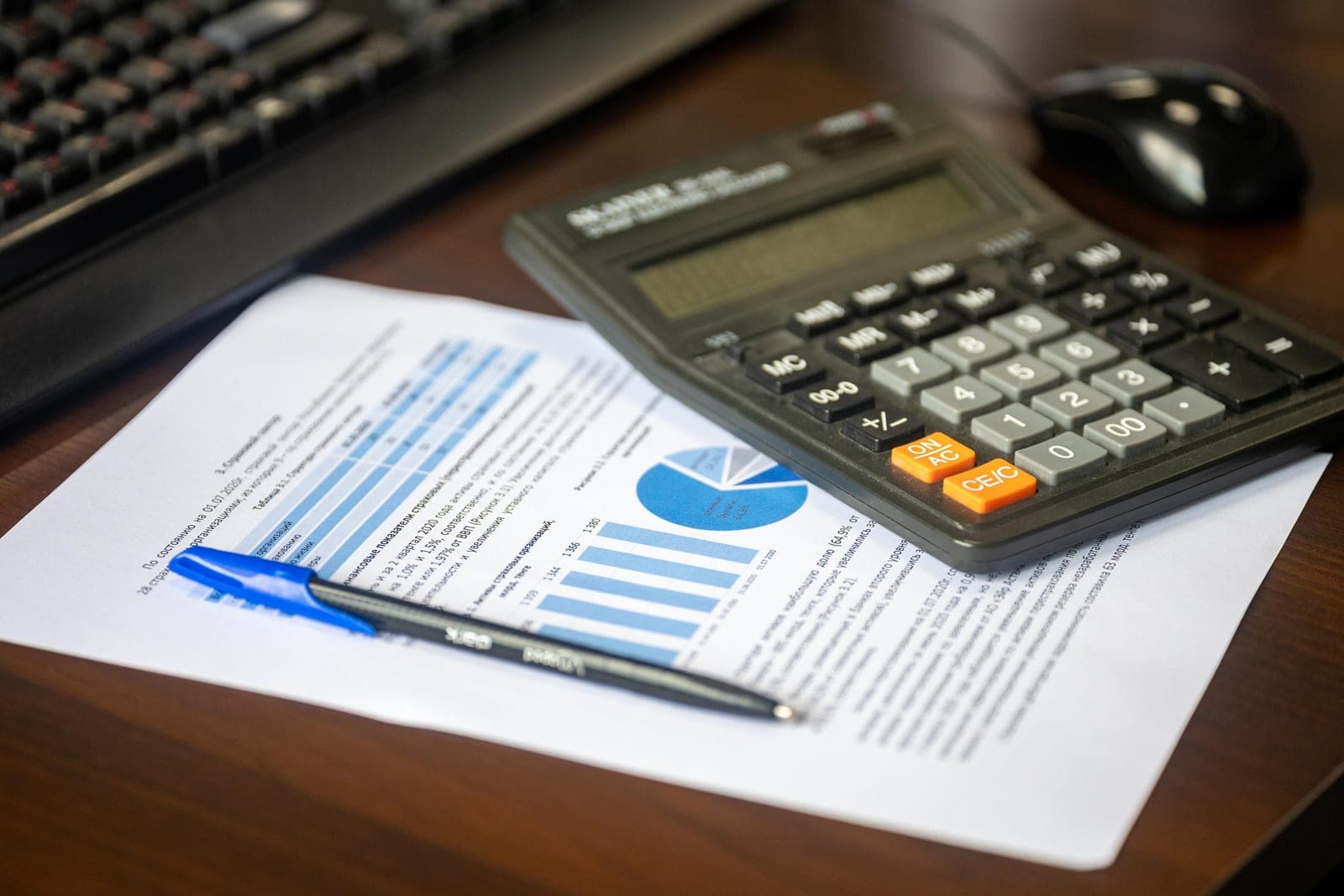 Calculator, pen and a financial report with charts on a desk, representing garment costing