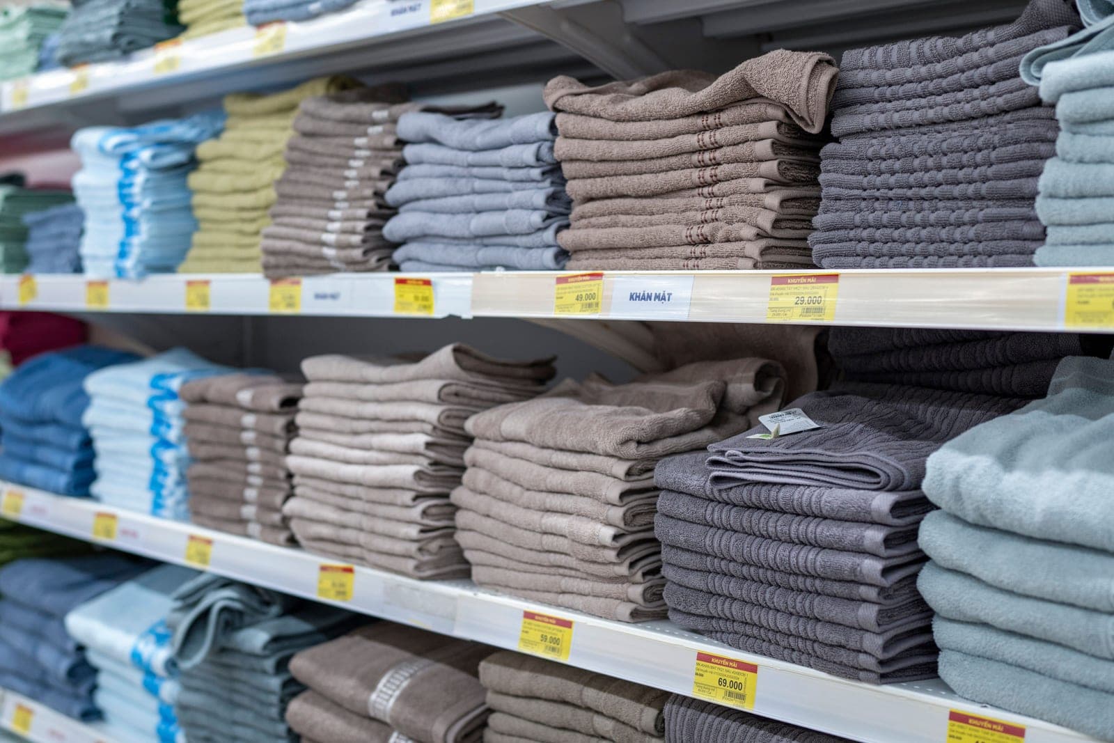 Shelves of neatly folded towels in many colours in a home-textiles retail store