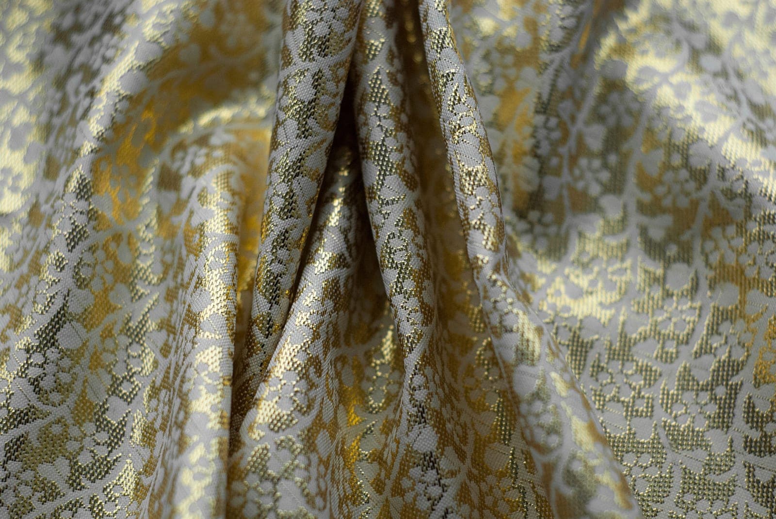 Close-up of gold and silver jacquard brocade fabric with an intricate woven floral pattern