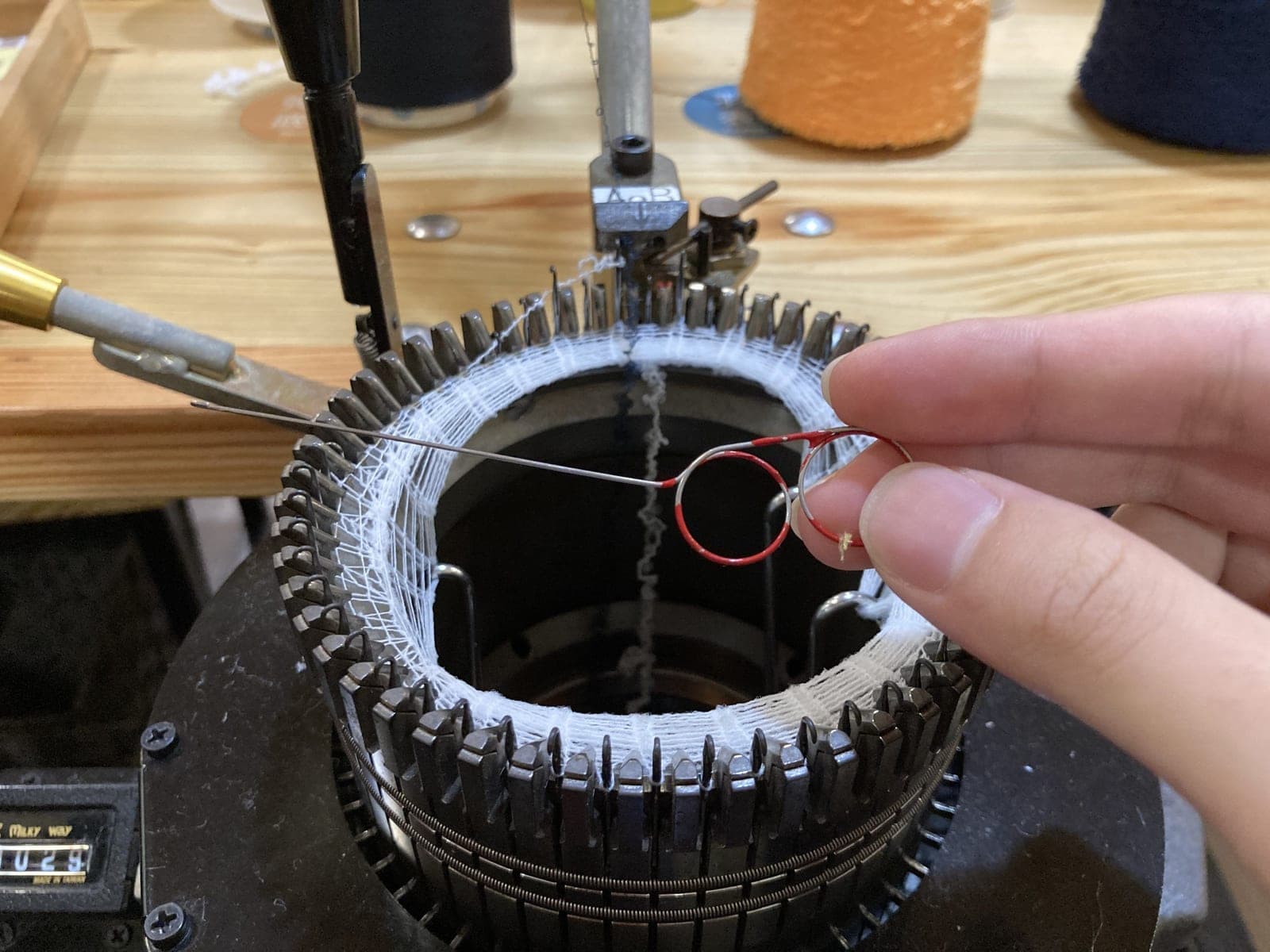 Circular knitting machine interlooping yarn into a tube of knitted fabric