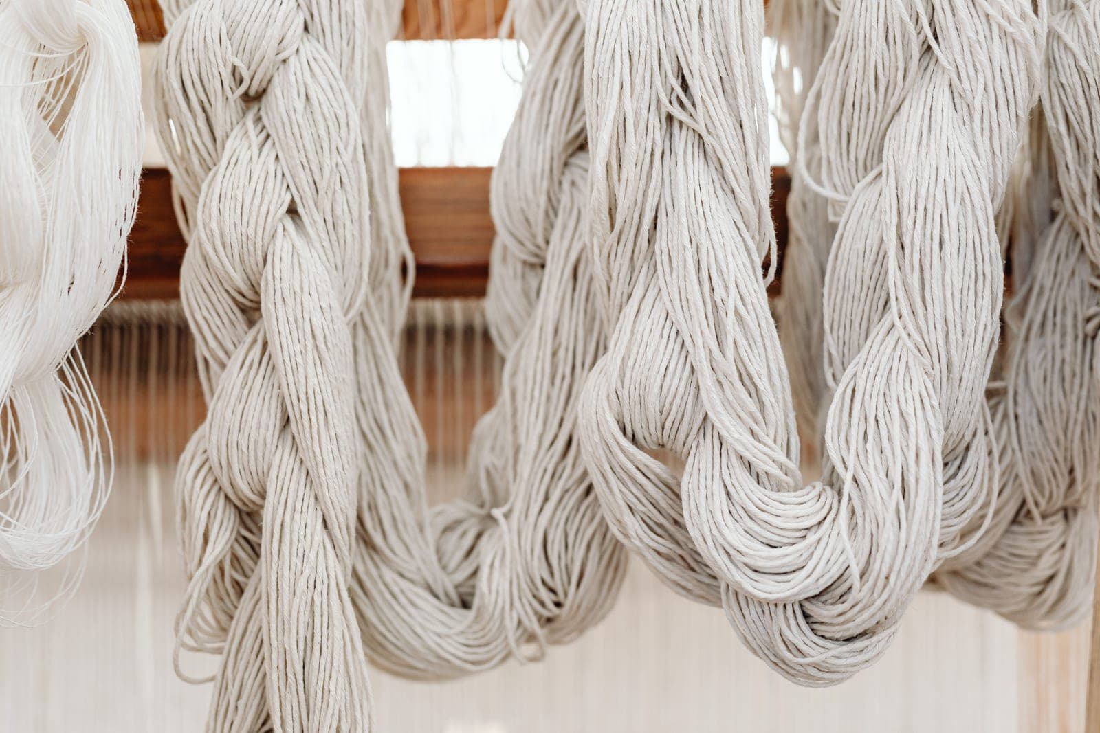 Hanks of white cotton yarn hanging, the kind of yarn that is mercerised for lustre and strength