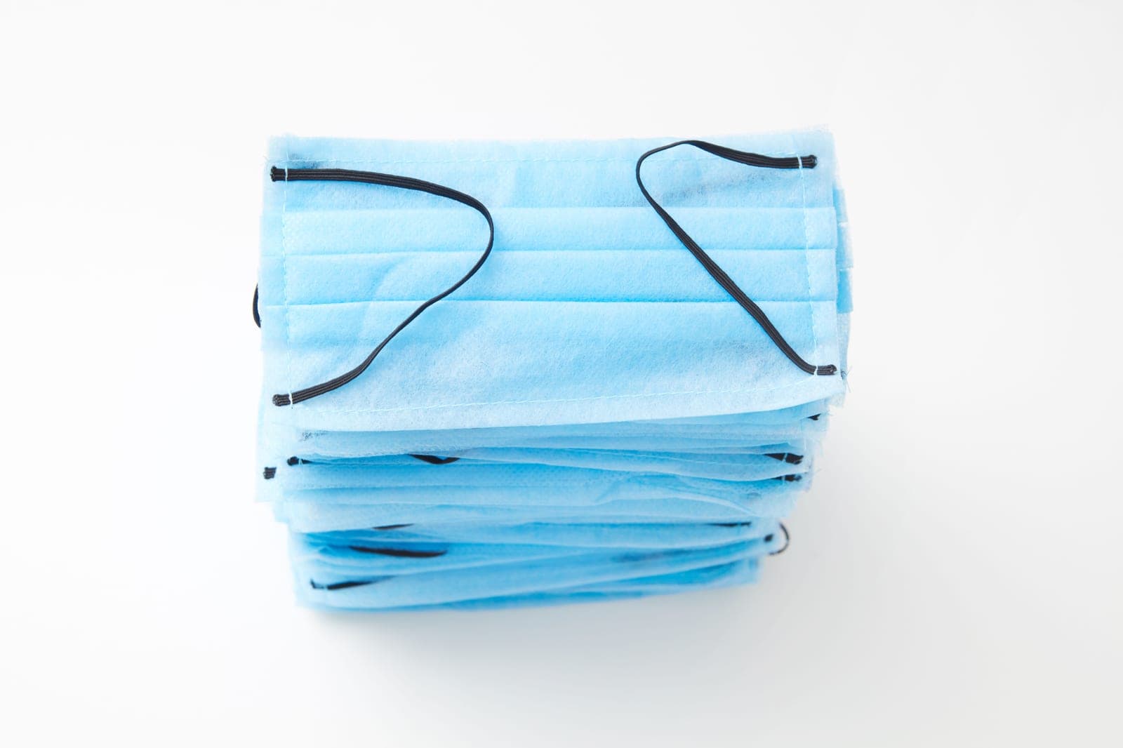 Stack of blue three-ply surgical face masks made from non-woven fabric
