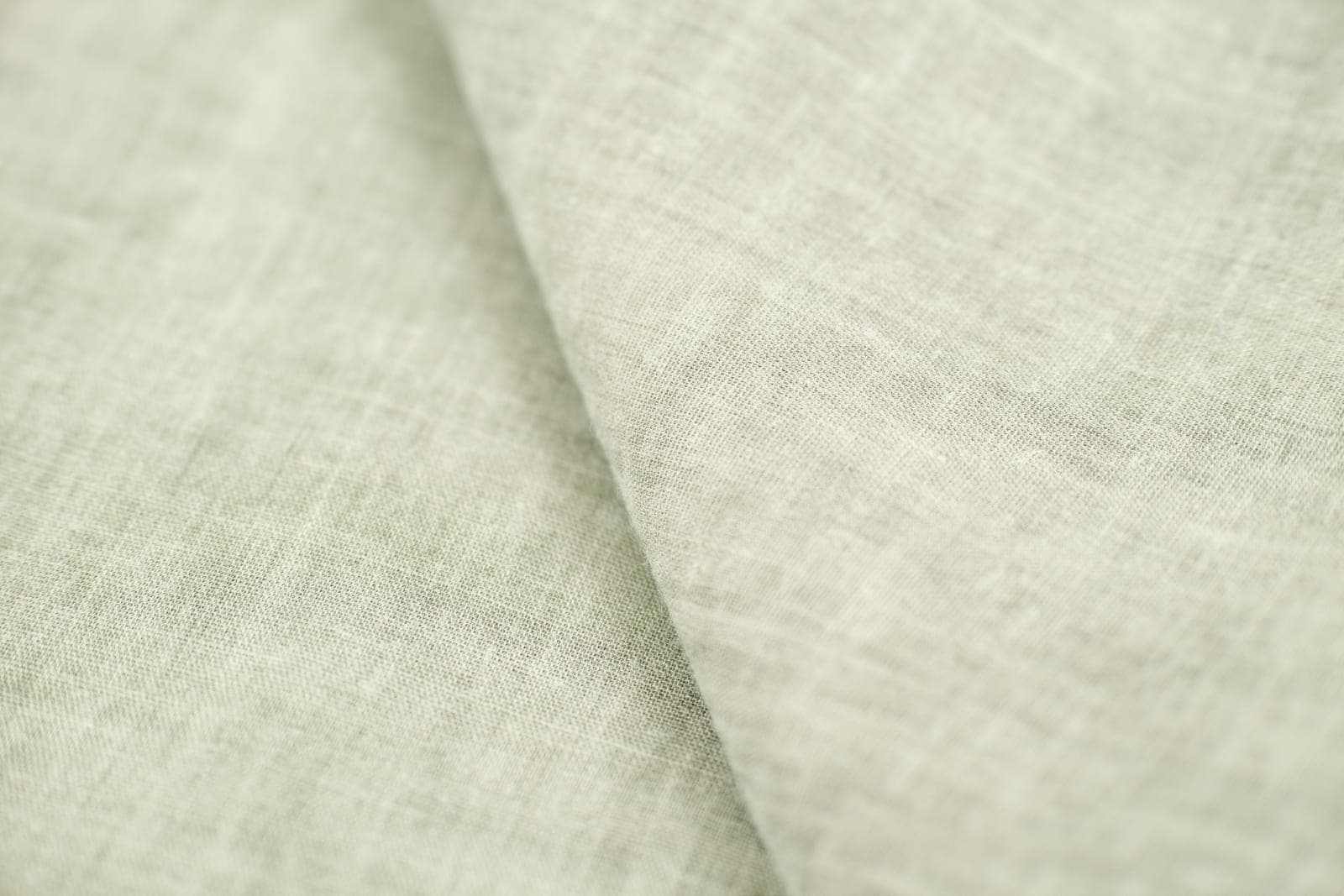 Close-up of a light linen fabric showing the simple over-under plain weave structure