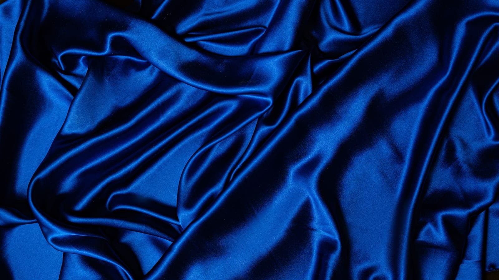 Draped blue satin fabric showing the smooth, lustrous surface of a satin weave