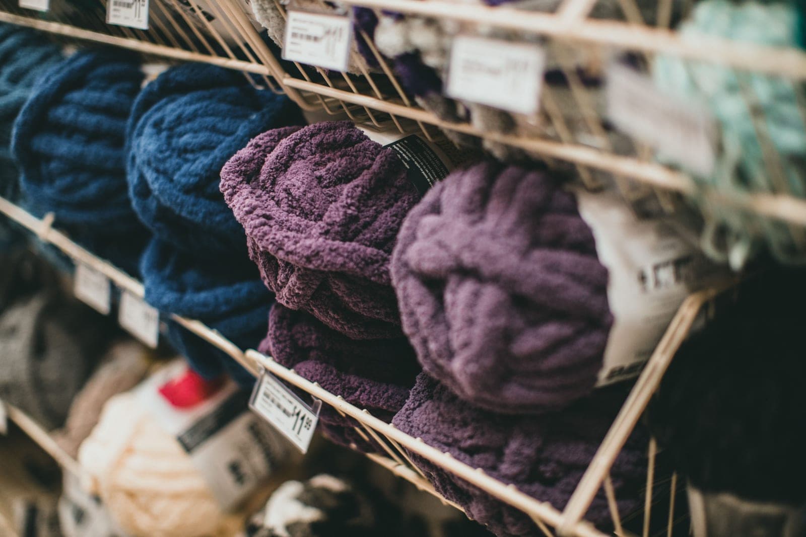 Shelves of different yarns in navy, purple and cream showing a variety of yarn types
