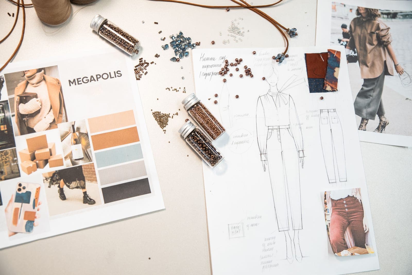 Fashion design workspace with a technical flat sketch of a garment, mood board and fabric swatches used to build a tech pack