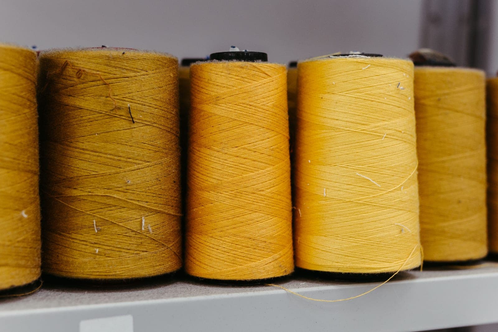 Row of yellow yarn cones on a shelf, the yarn whose fineness is described by its count