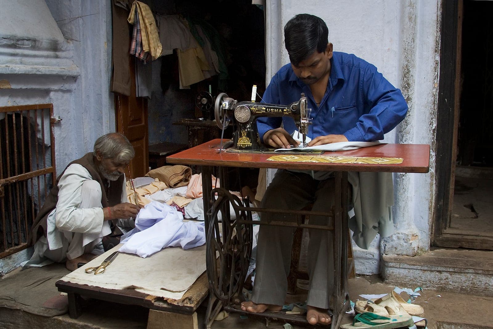 Tailors stitching garments at sewing machines in a tailor shop