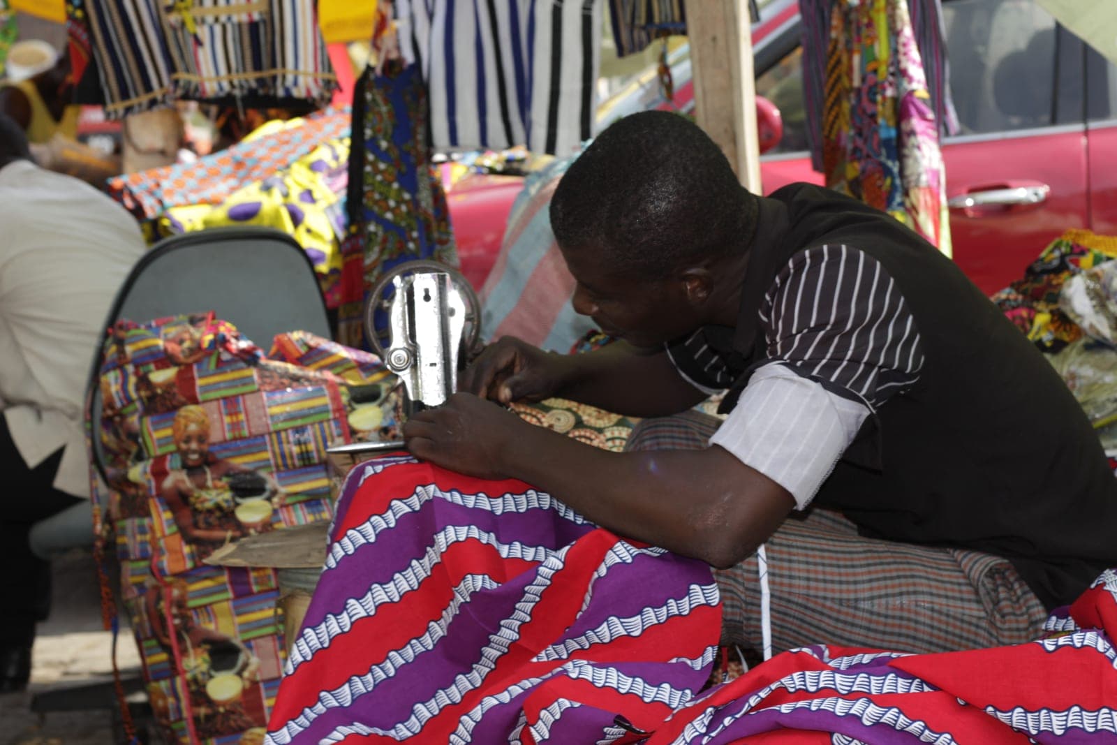 Tailor stitching patterned fabric on a sewing machine in a tailoring workshop