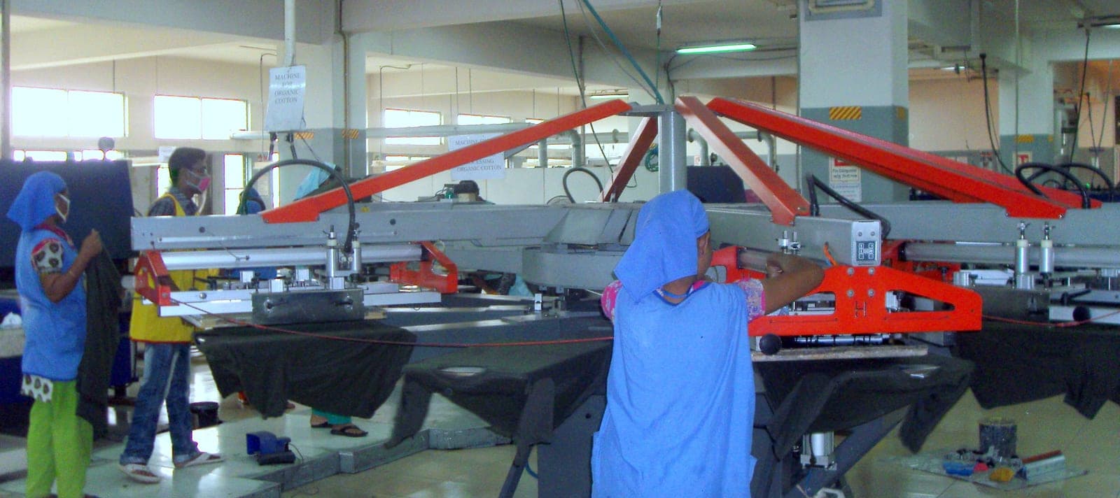 Operators working at a screen-printing station on a garment production floor